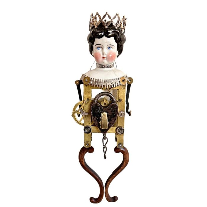 assemblage sculpture made from antique clock parts, vintage porcelain doll head, antique heart shaped iron lock, and other found objects